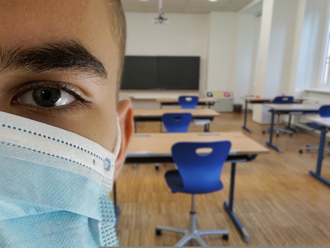 Foto van iemand met een mondkapje in een klaslokaal